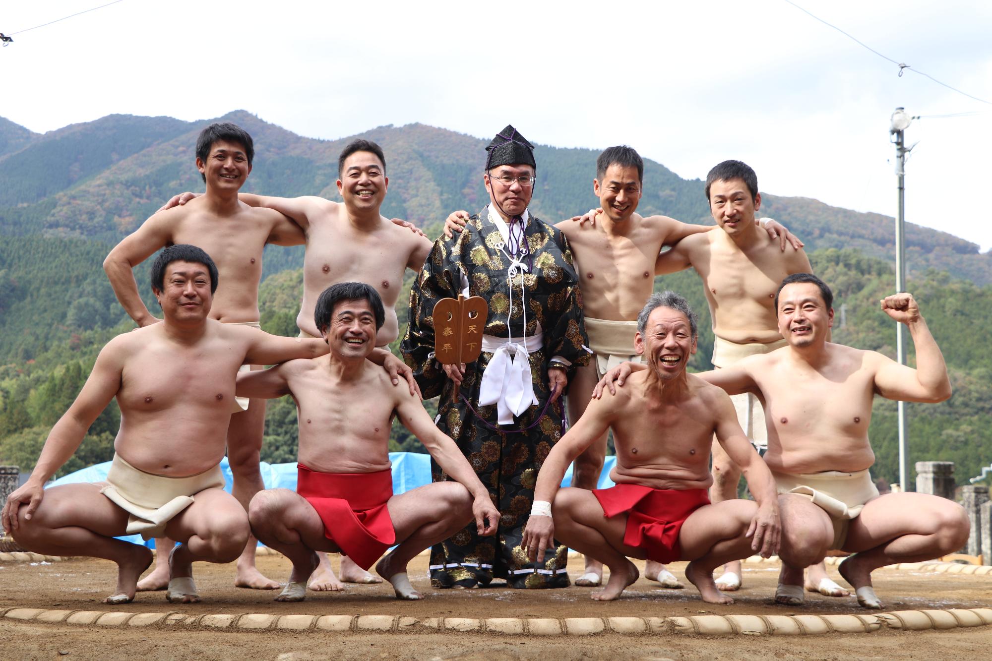 還暦相撲に参加した宝殿神社奉納相撲実行委員会力士会の力士らが並んで笑っている写真