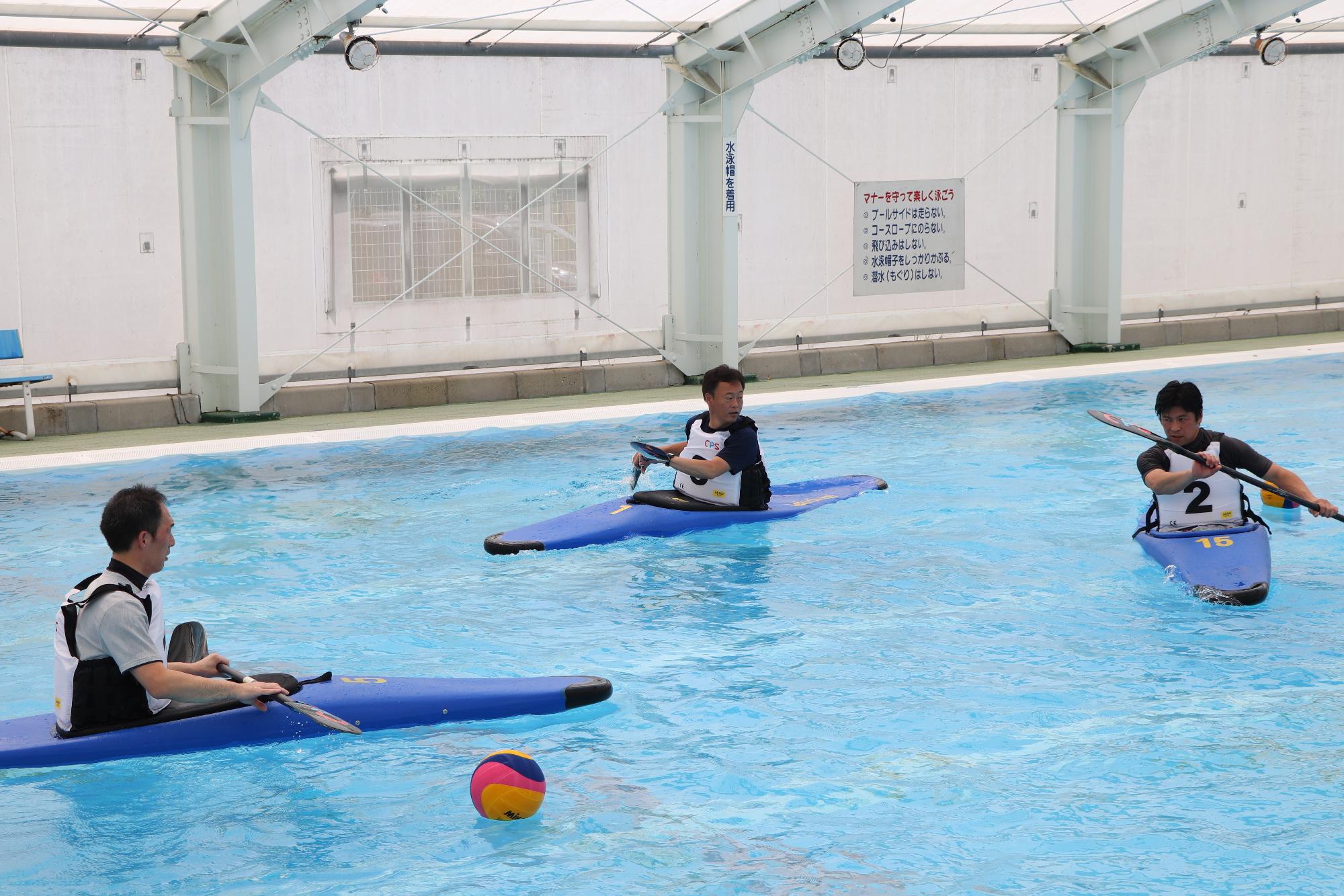 カヌーポロ選手養成講座に参加し、プールでカヌーを漕ぐ練習をしている参加者らの写真