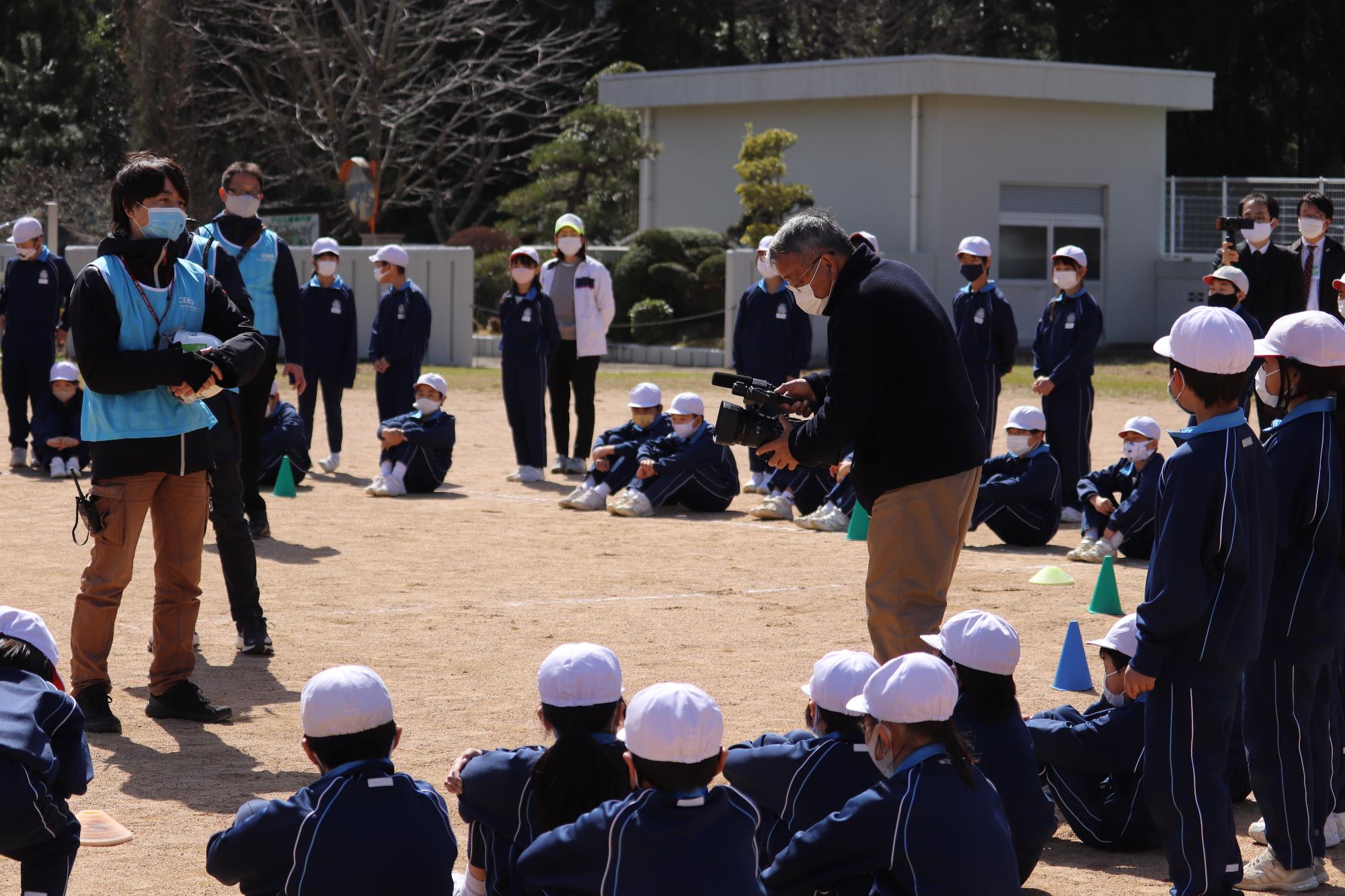 ドローンの見学会で研究員の吉田さんに質問する波賀小学校児童らの写真