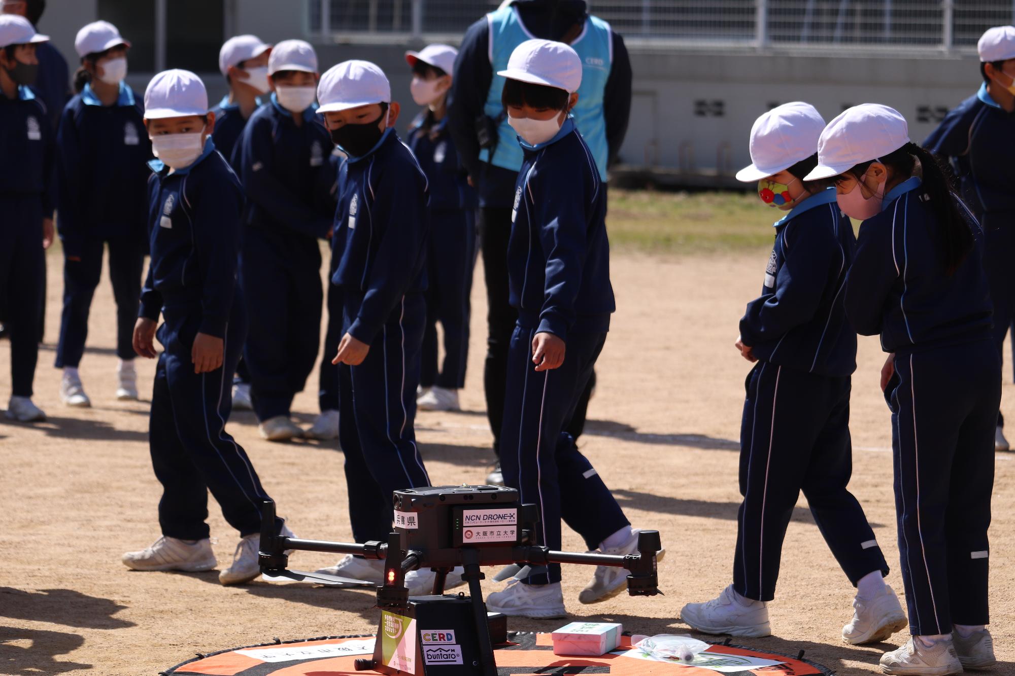 ドローンを間近で見学する波賀小児童らの写真