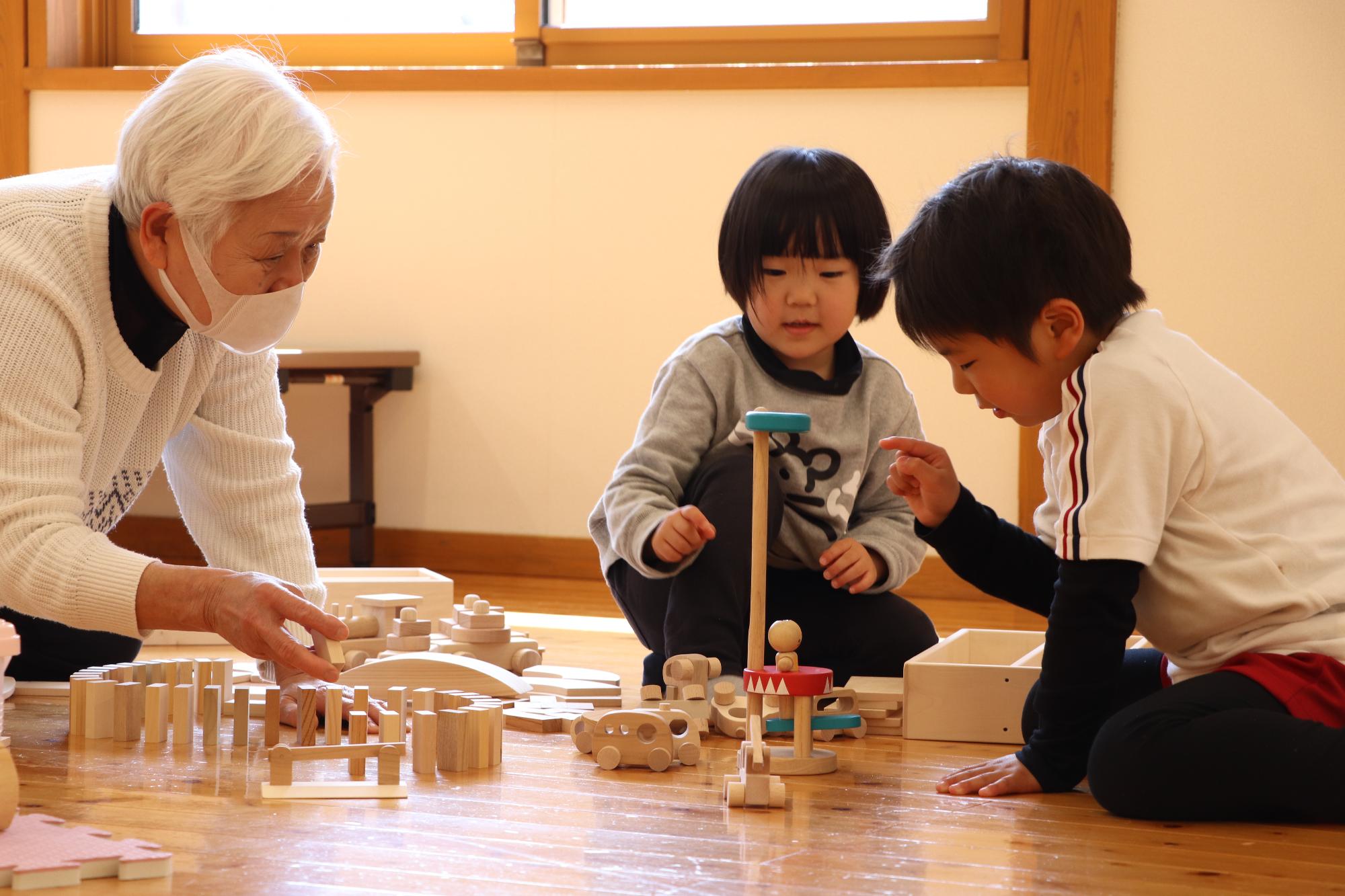 祖母、孫が木のおもちゃでいっしょに遊んでいる写真