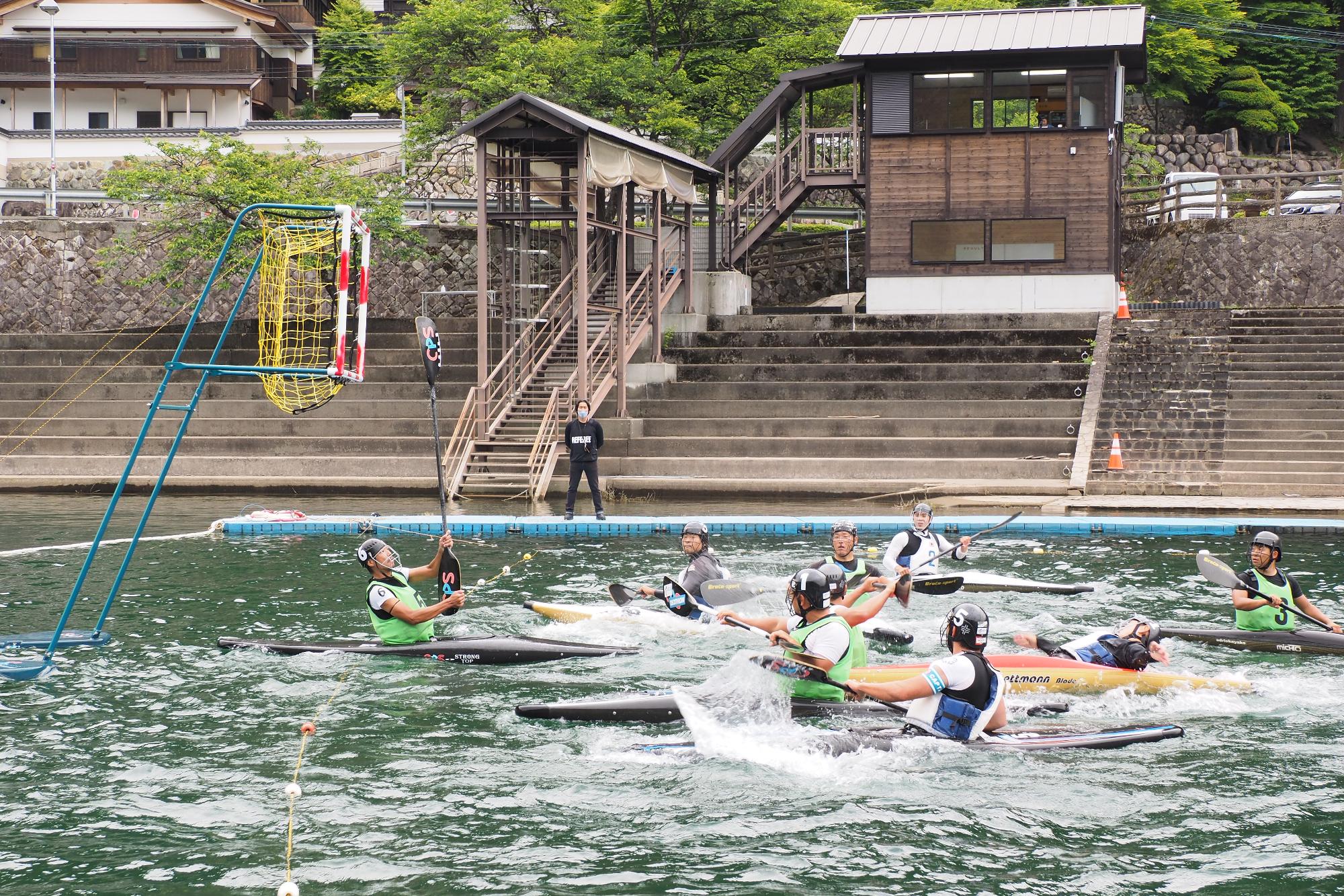 湖につくらた水上のコートで1人乗りのカヌーに乗りボールを奪い合っている写真