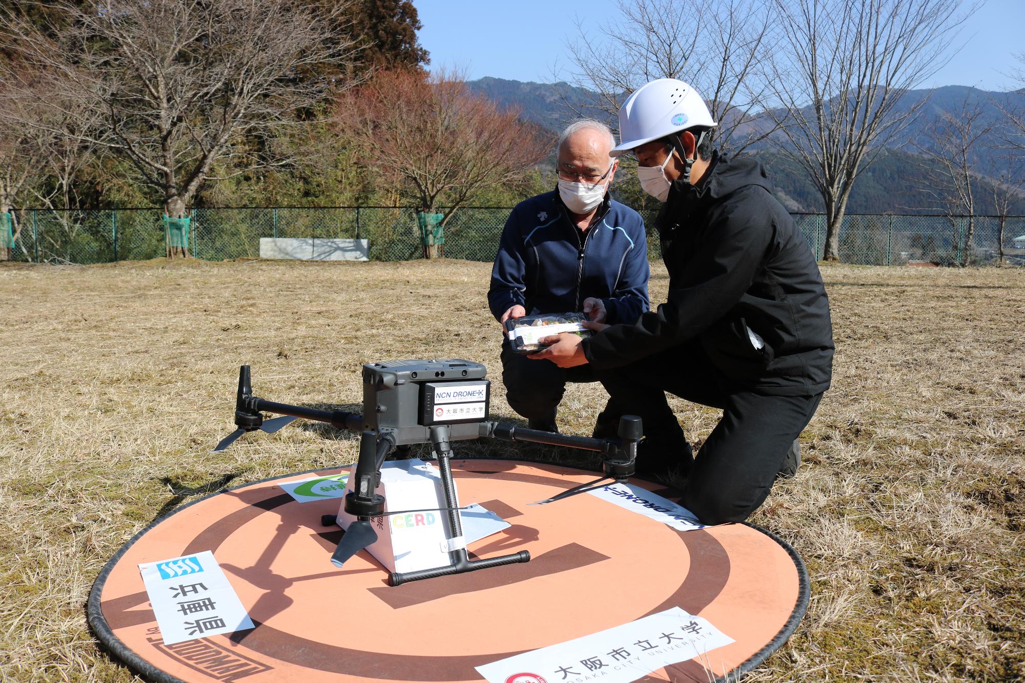 ドローンから取り出した弁当を住民が受取っている様子