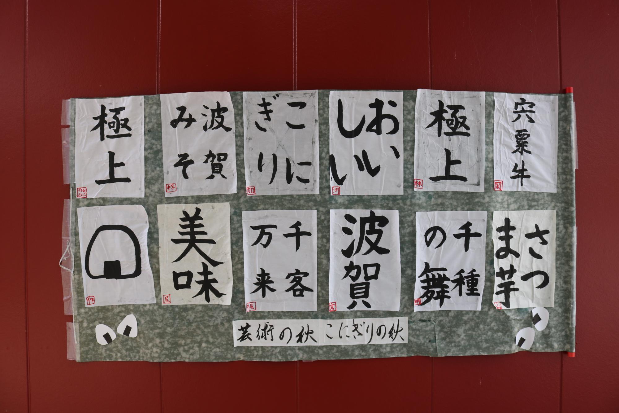 「こにぎり」「おいしい」など参加児童が書いた習字がお店の外壁に貼り出されている写真