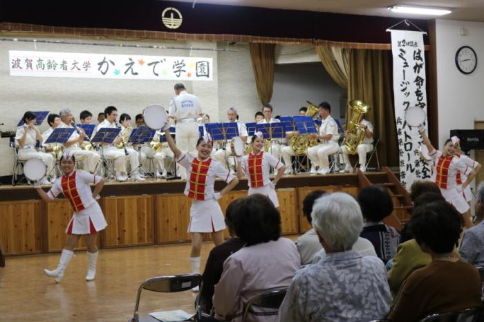 白いコスチュームでダンスを踊る女性と後ろで演奏する兵庫県警察音楽隊の写真