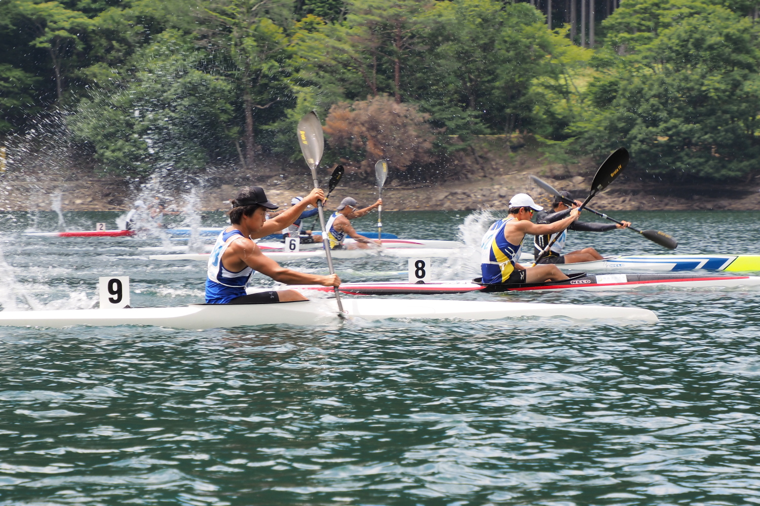 音水湖に設置されたコース上でカヌーを漕いで着順を競う選手らの写真