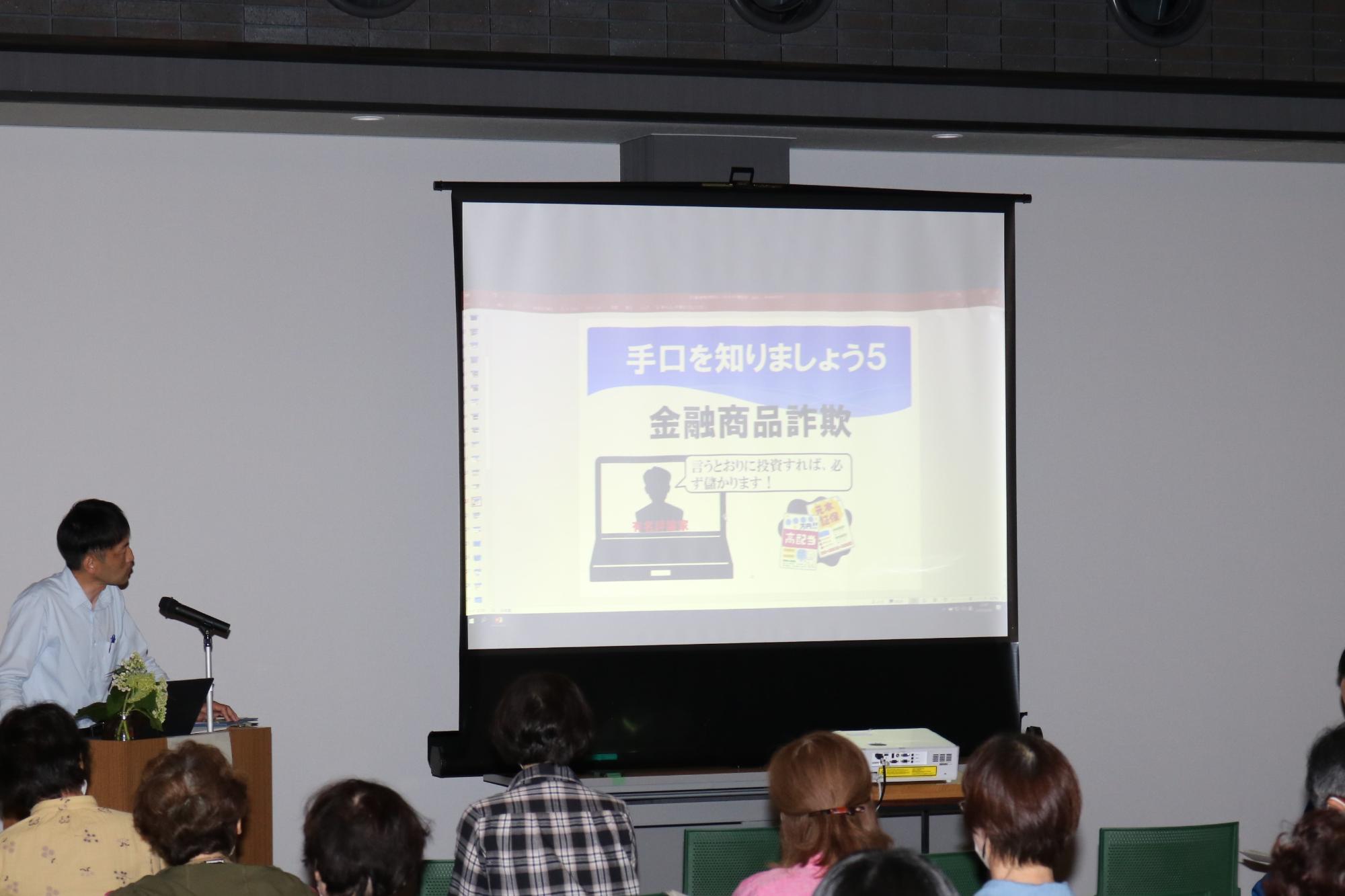 宍粟署員がスライドショーを使って特殊詐欺の手口を説明している写真