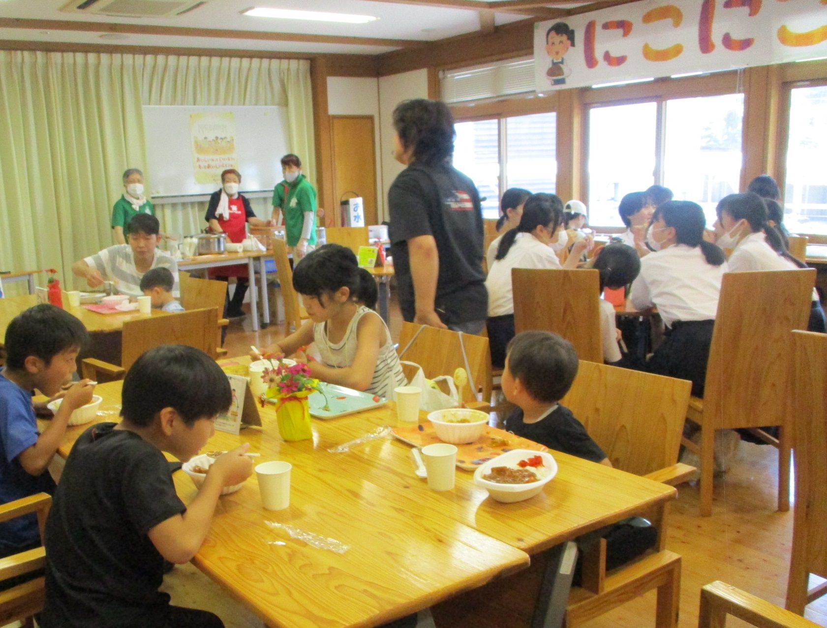 児童らとその保護者などが波賀町で子ども食堂を運営するにこにこ食堂で提供されるカレーライスを食べている写真
