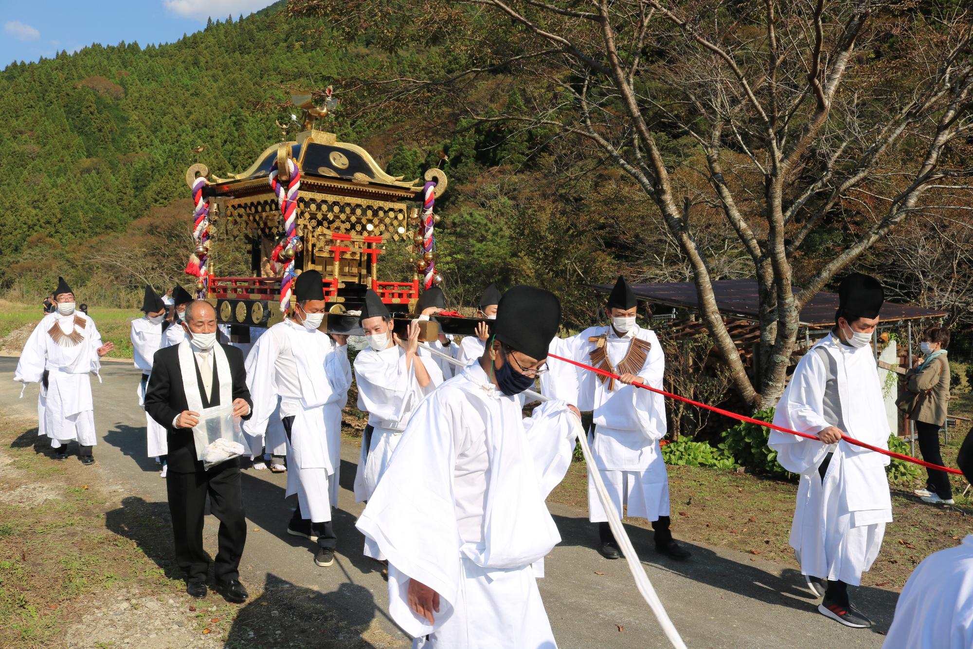 行列の中心で神輿を担いで歩いている写真