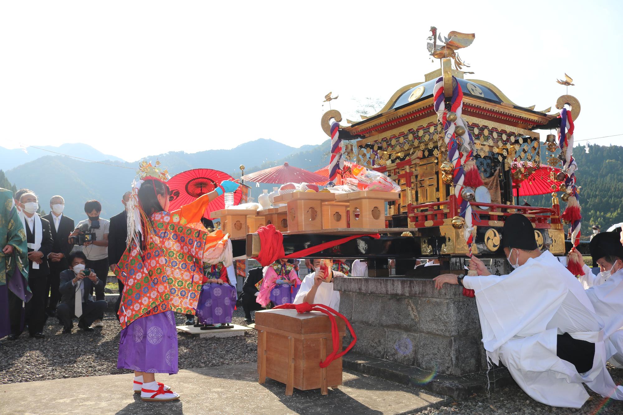 少女神子が神にお供えをしている写真