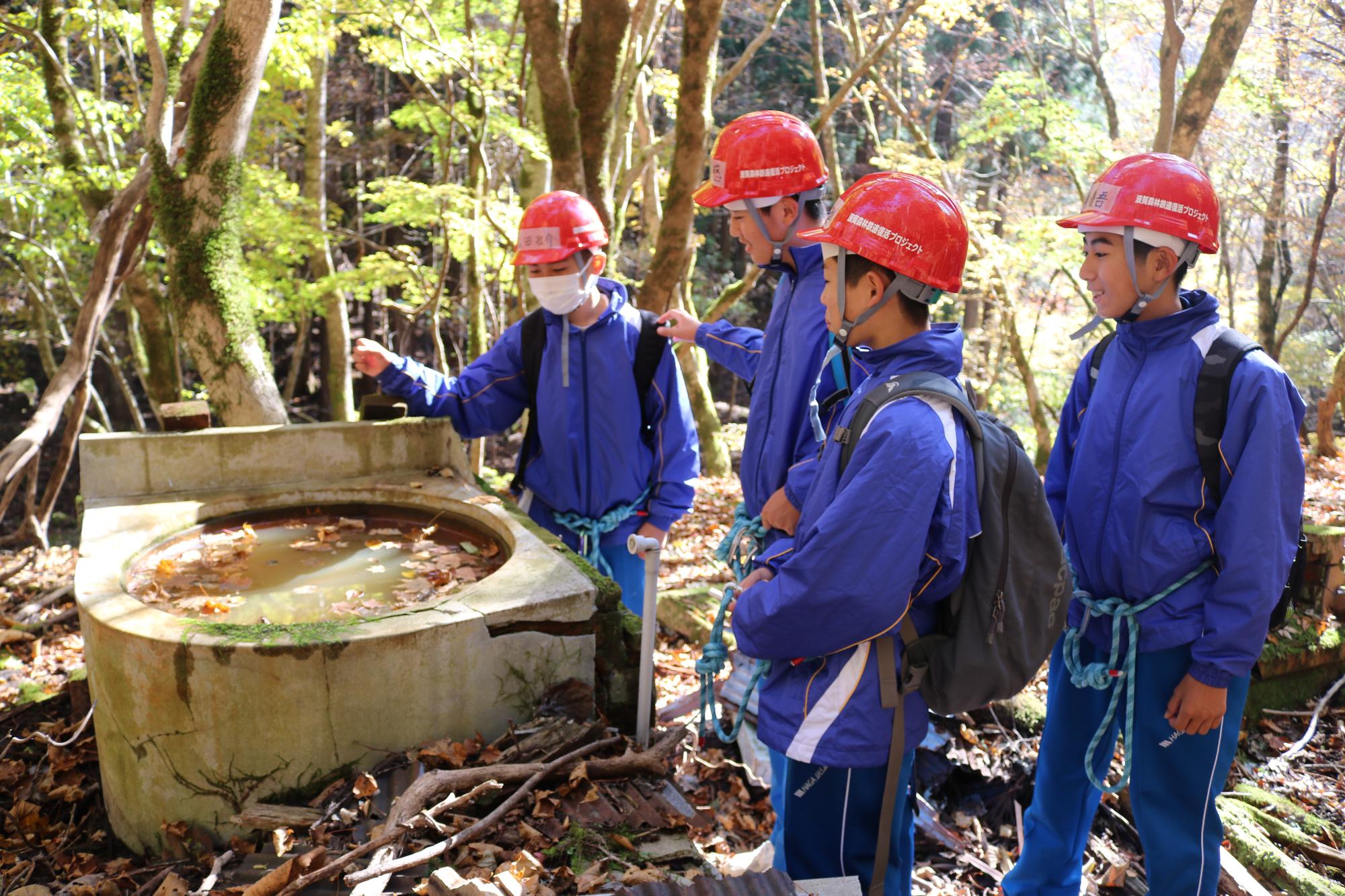 宿舎跡でつかわれていた風呂釜を4人の生徒が見学している写真