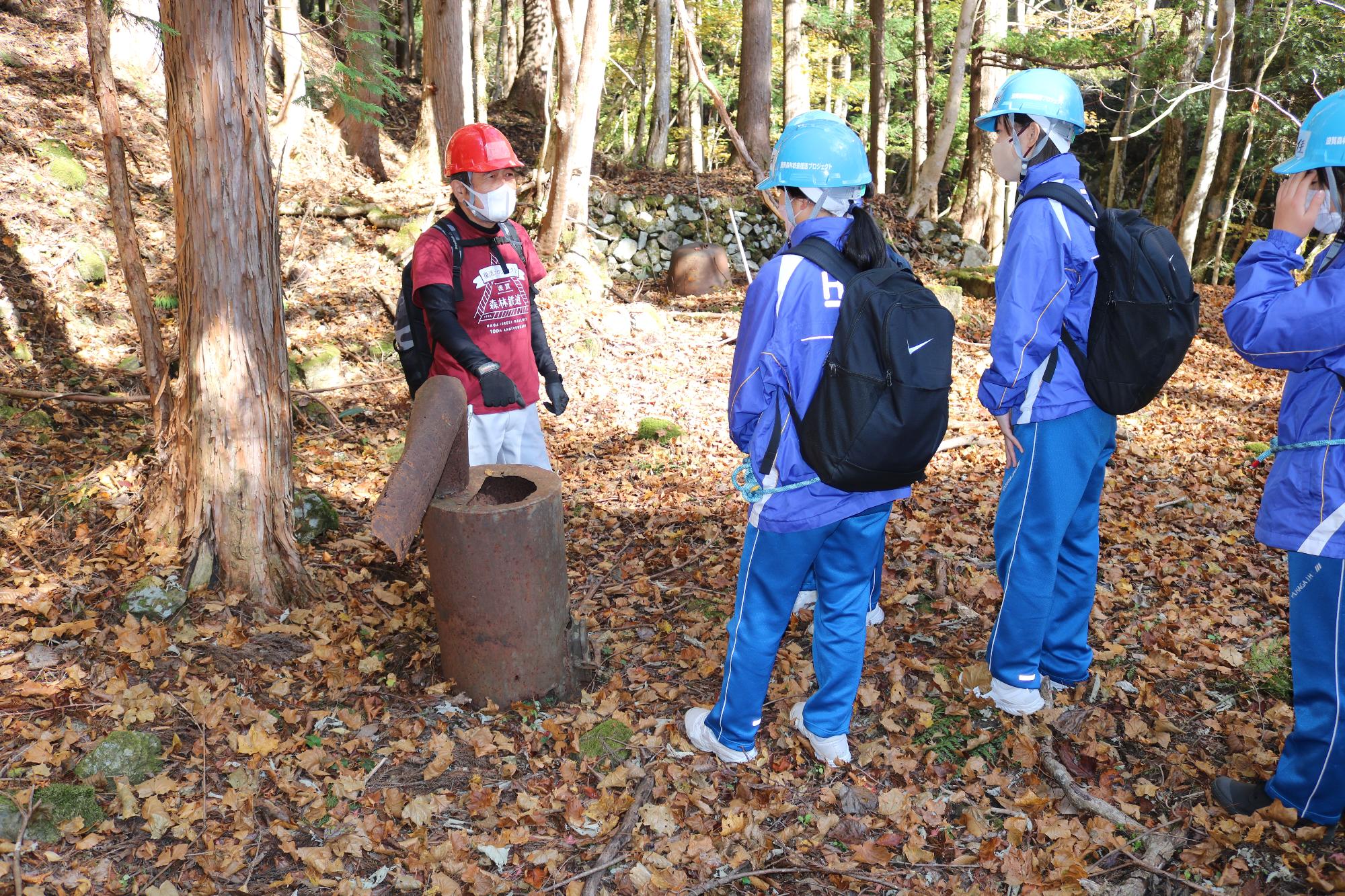 旧宿泊地で案内人の説明を聞く学生たちの写真