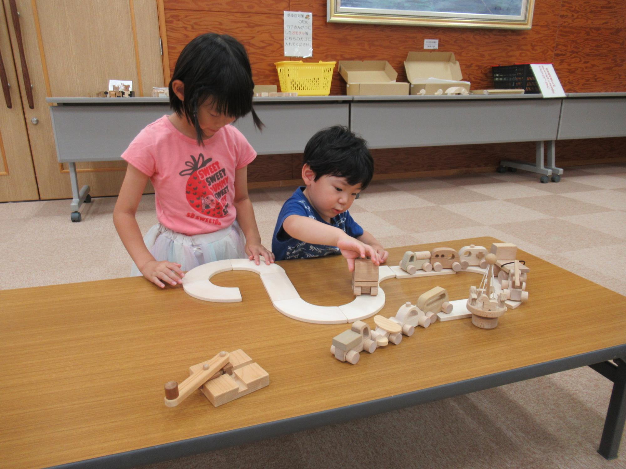 道やトラックの形をした木のおもちゃで子どもが遊んでいる写真