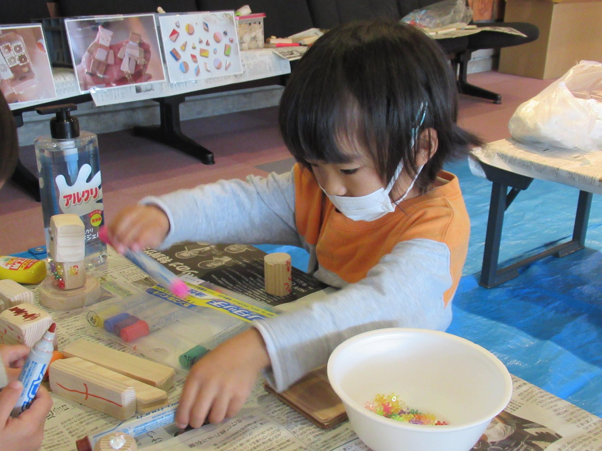 子どもが木の板にマジックで絵を描いたり色を塗ったりしている写真