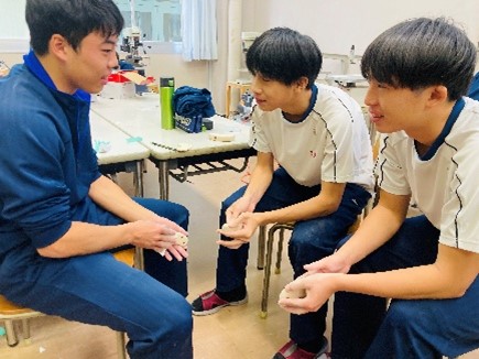 千種高校の生徒3名が木のおもちゃにサンドペーパーをかけて仕上げをしているようす