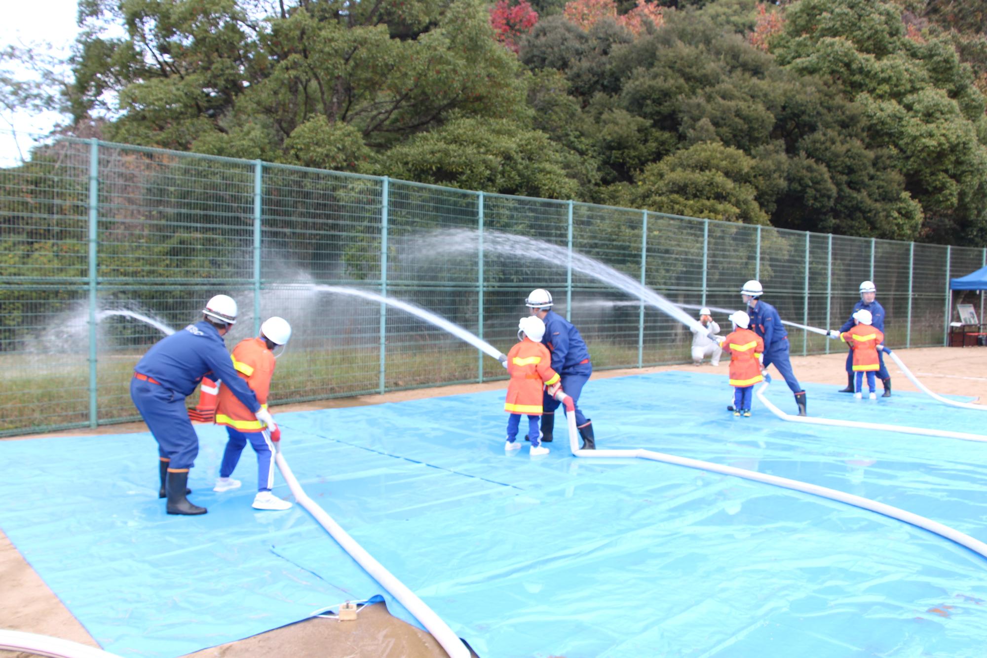 子どもたちが消防団員と防災訓練を行っている画像