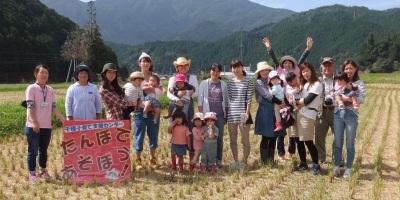 千種子育て支援センターの主催するイベント「たんぼで遊ぼう」の参加者が田んぼで遊んだあとに記念写真を撮っている様子の写真