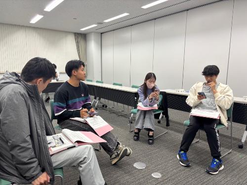 男性3名と女性1名が会議で協議をしている