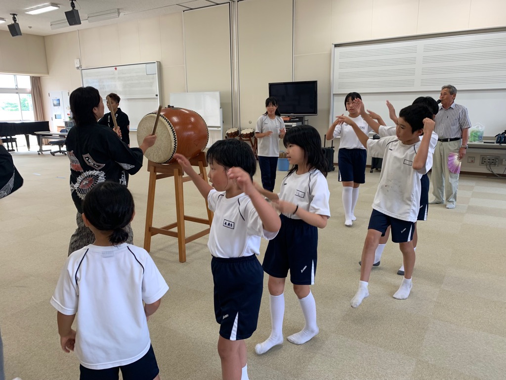 盆踊り教室で児童が太鼓に合わせて踊っている様子の写真