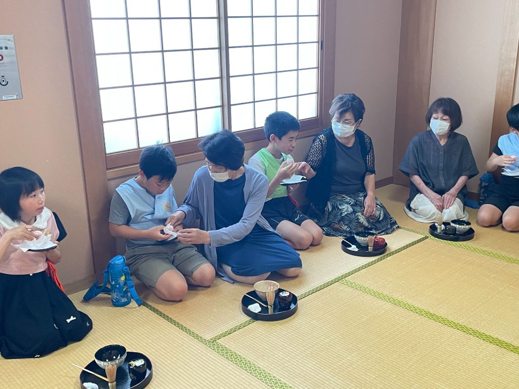 茶菓子を食べる作法を教わる参加者たち