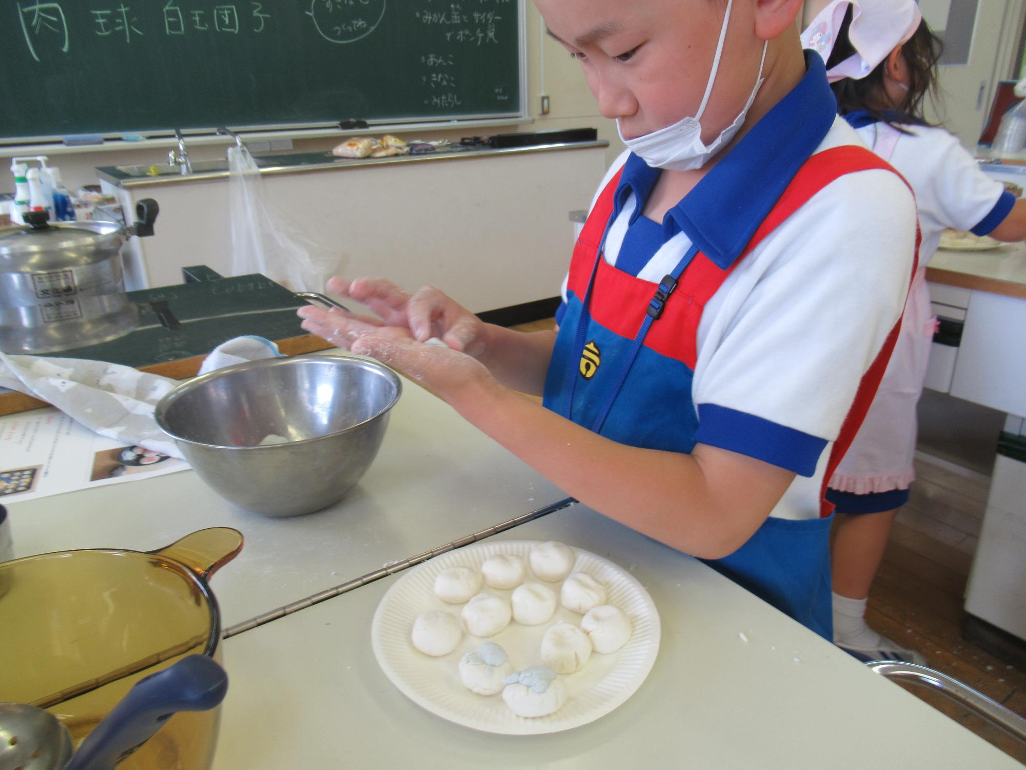 青く着色させた生地を成形し、肉球型の生地をつくる子ども