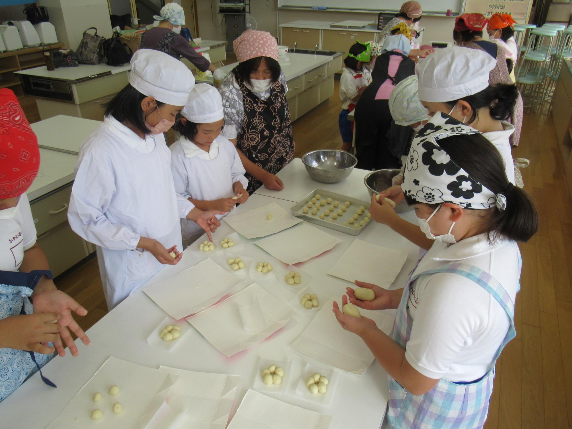 料理教室の参加者らが生地を小分けに丸めてドーナツ形に繋げる工程に挑戦している写真