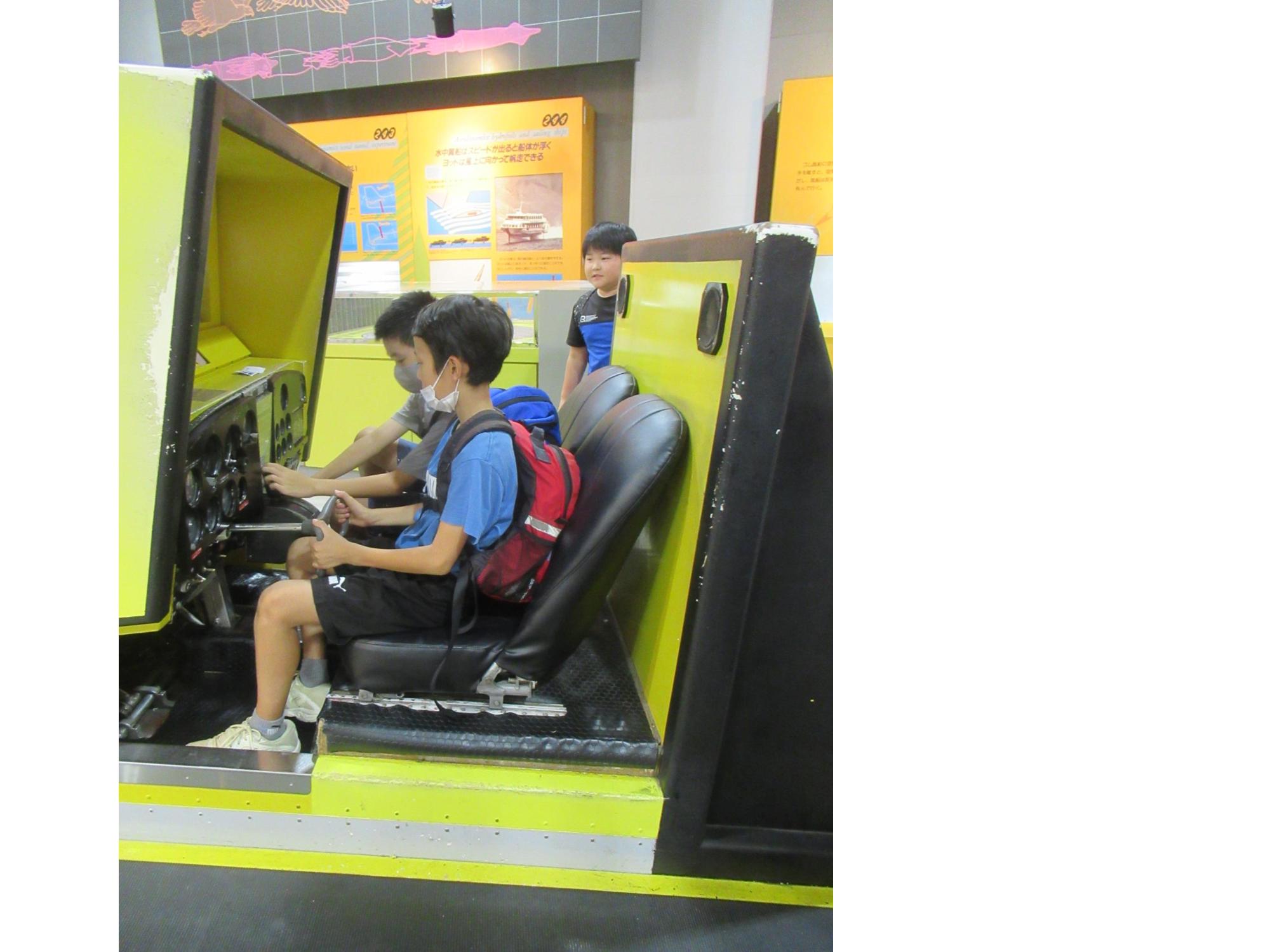 参加者がバンドー神戸青少年科学館の飛行機操縦体験コーナーで楽しんでいる写真