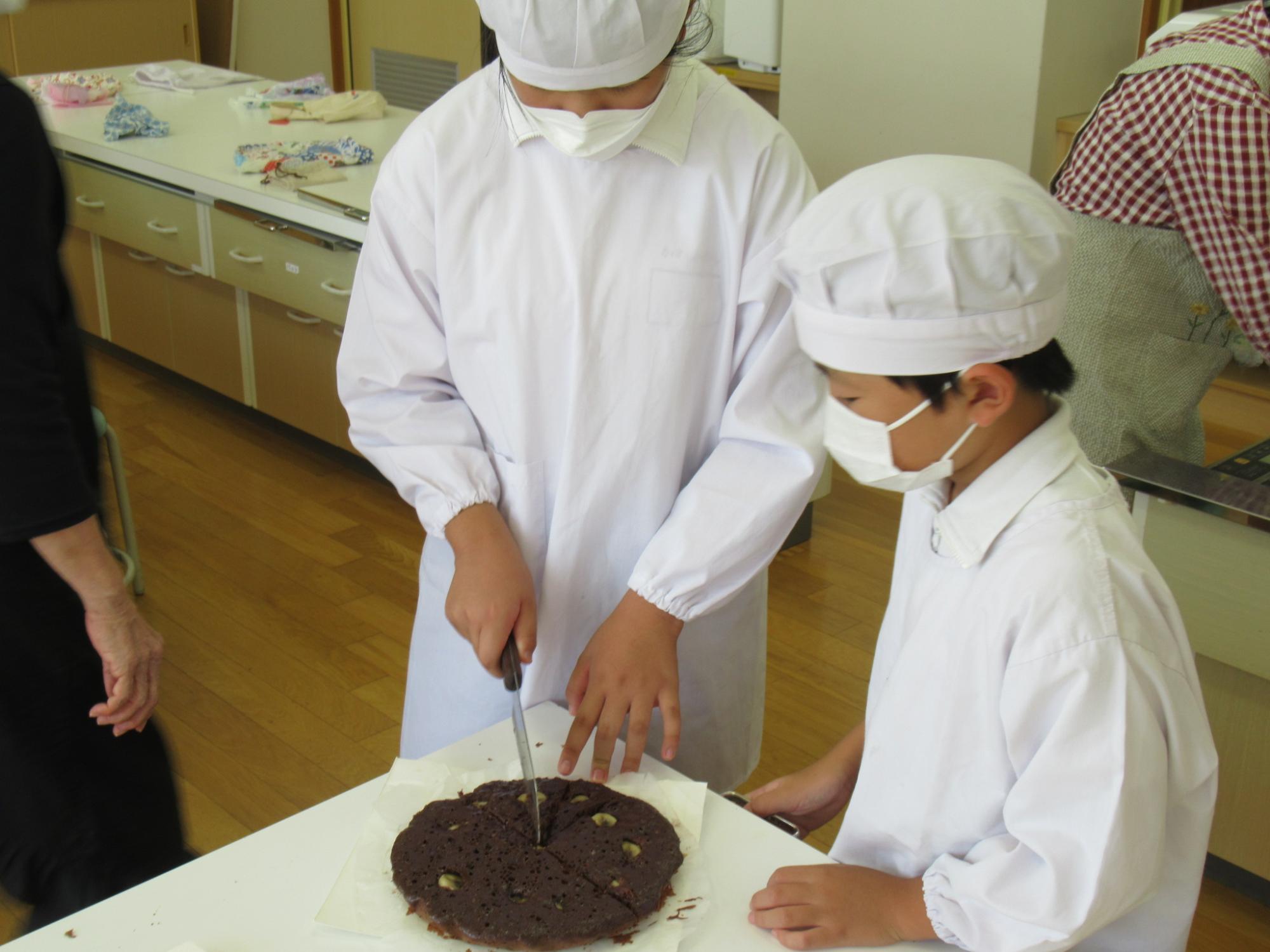 上級生の参加者がチョコケーキを16等分に切り分けている写真