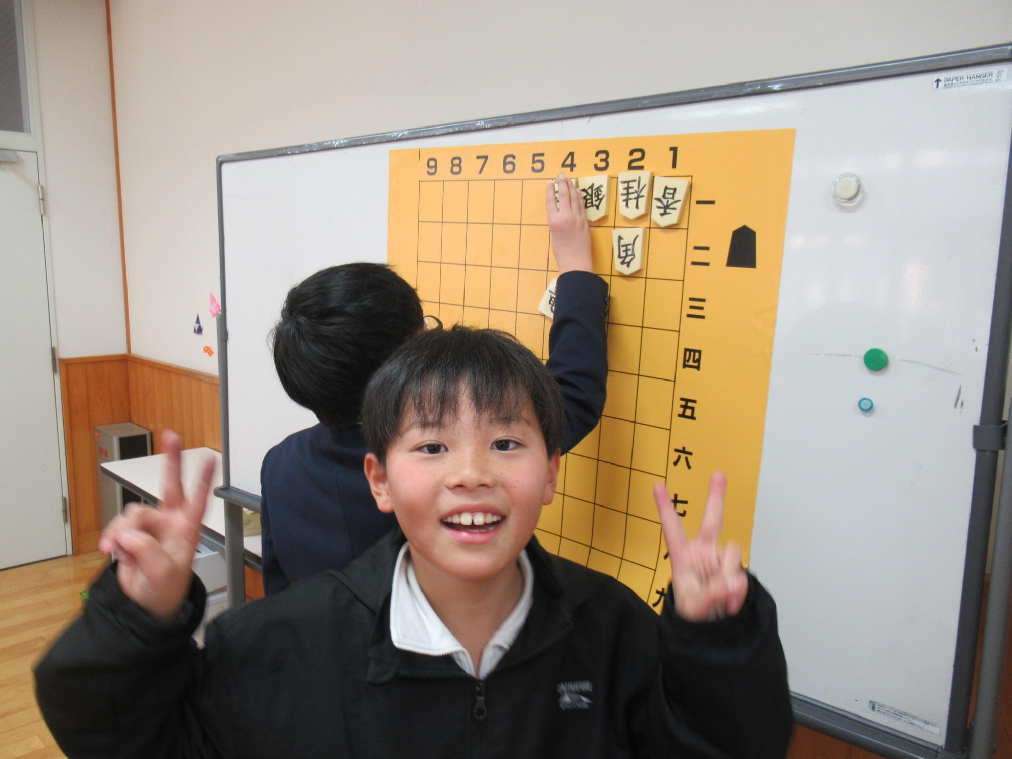難問の詰将棋を無事解くことができた参加者が正面を向いて喜んでいる写真