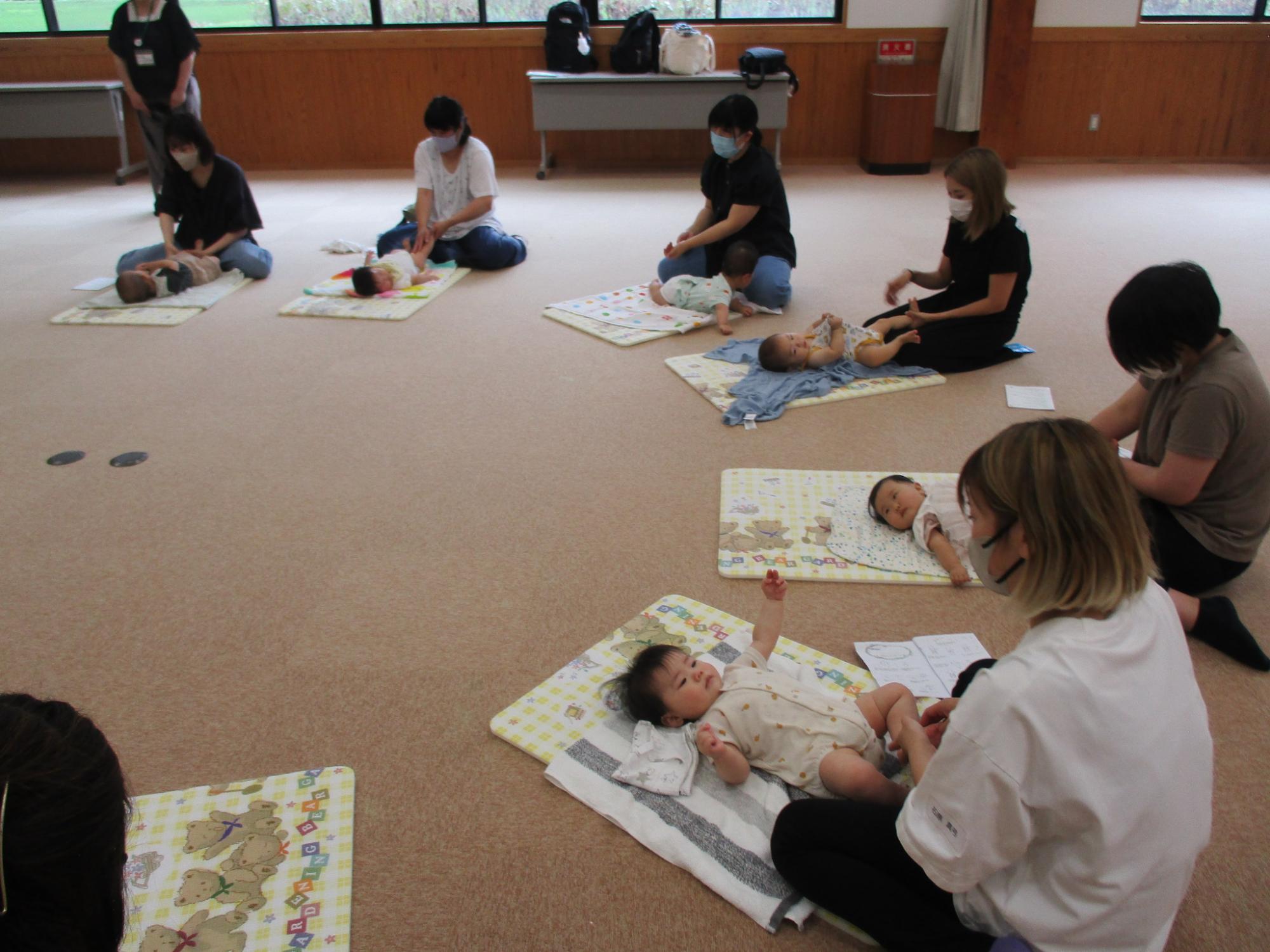 参加者が自身の赤ちゃんにベビーマッサージを実践し、リラックスした雰囲気の写真