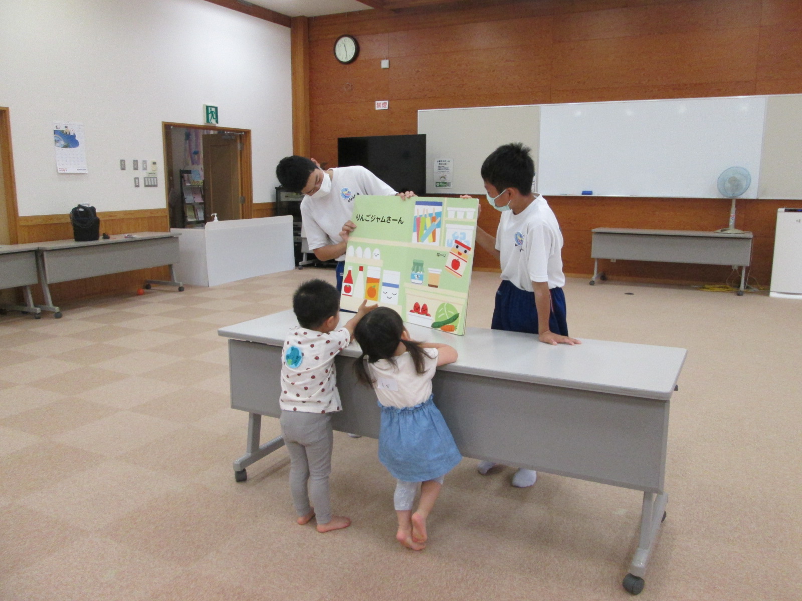 学遊館を訪れた子どもたちに紙芝居を読む中学生たちの写真