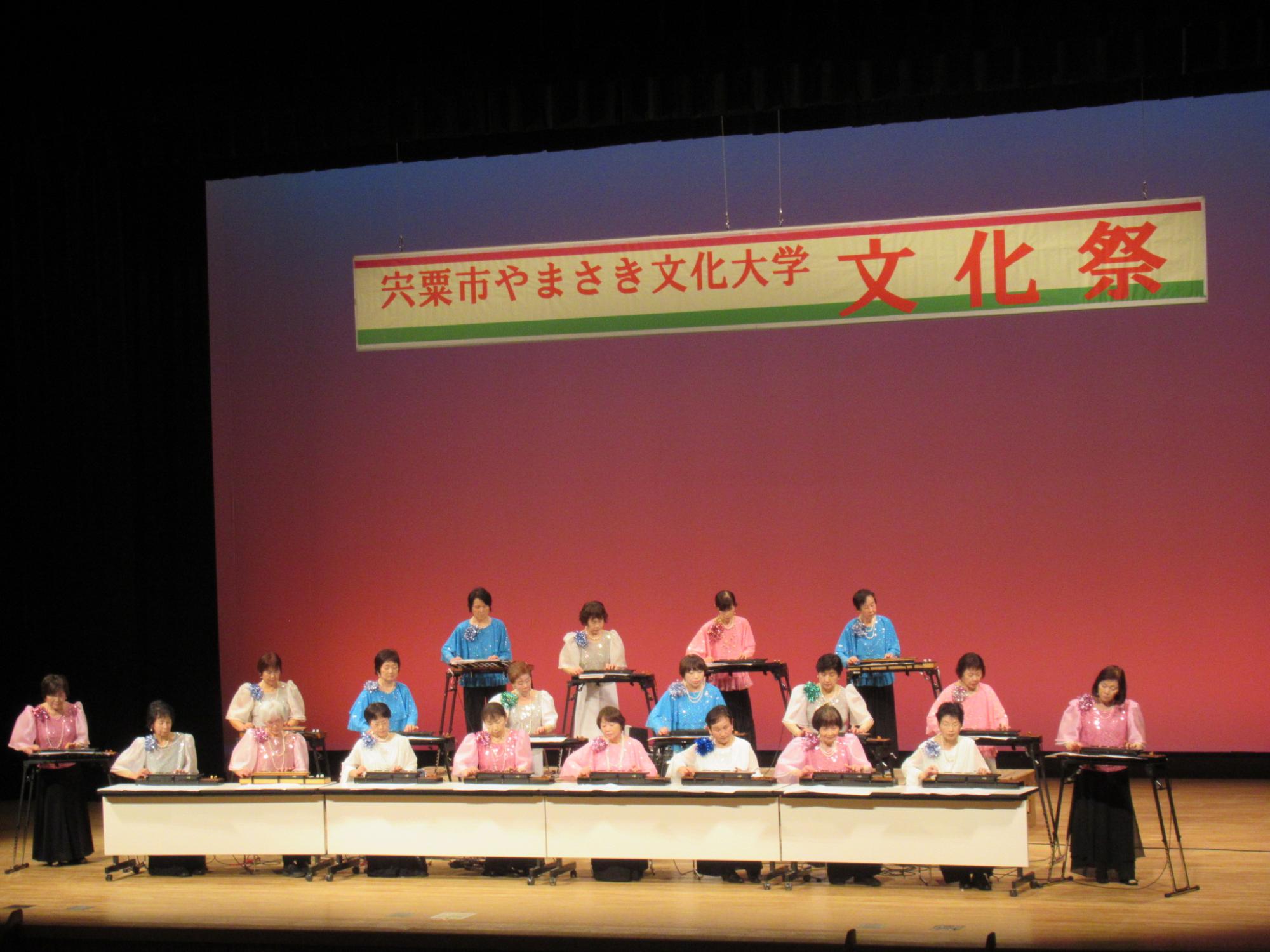 ステージ上で大正琴の演奏を披露する大正琴クラブの学生らの写真
