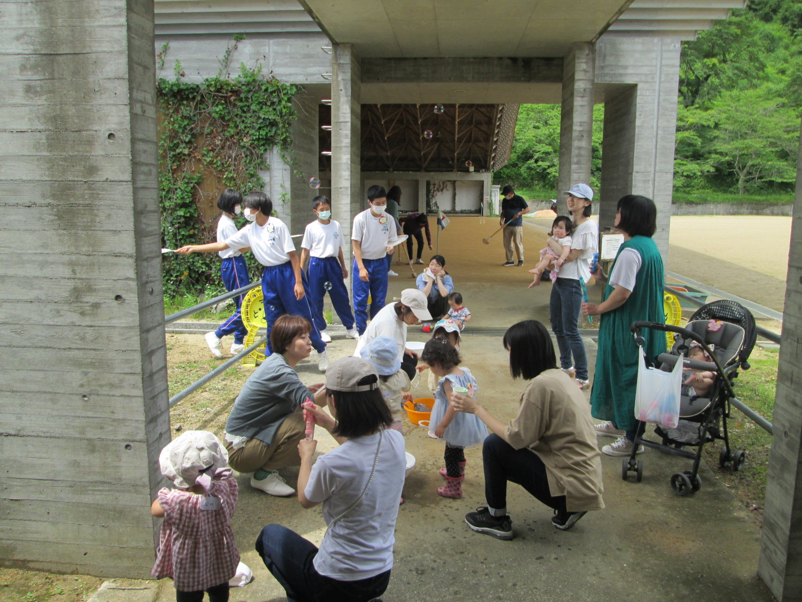 複数の親子が学遊館の屋外でしゃぼん玉遊びをしている写真