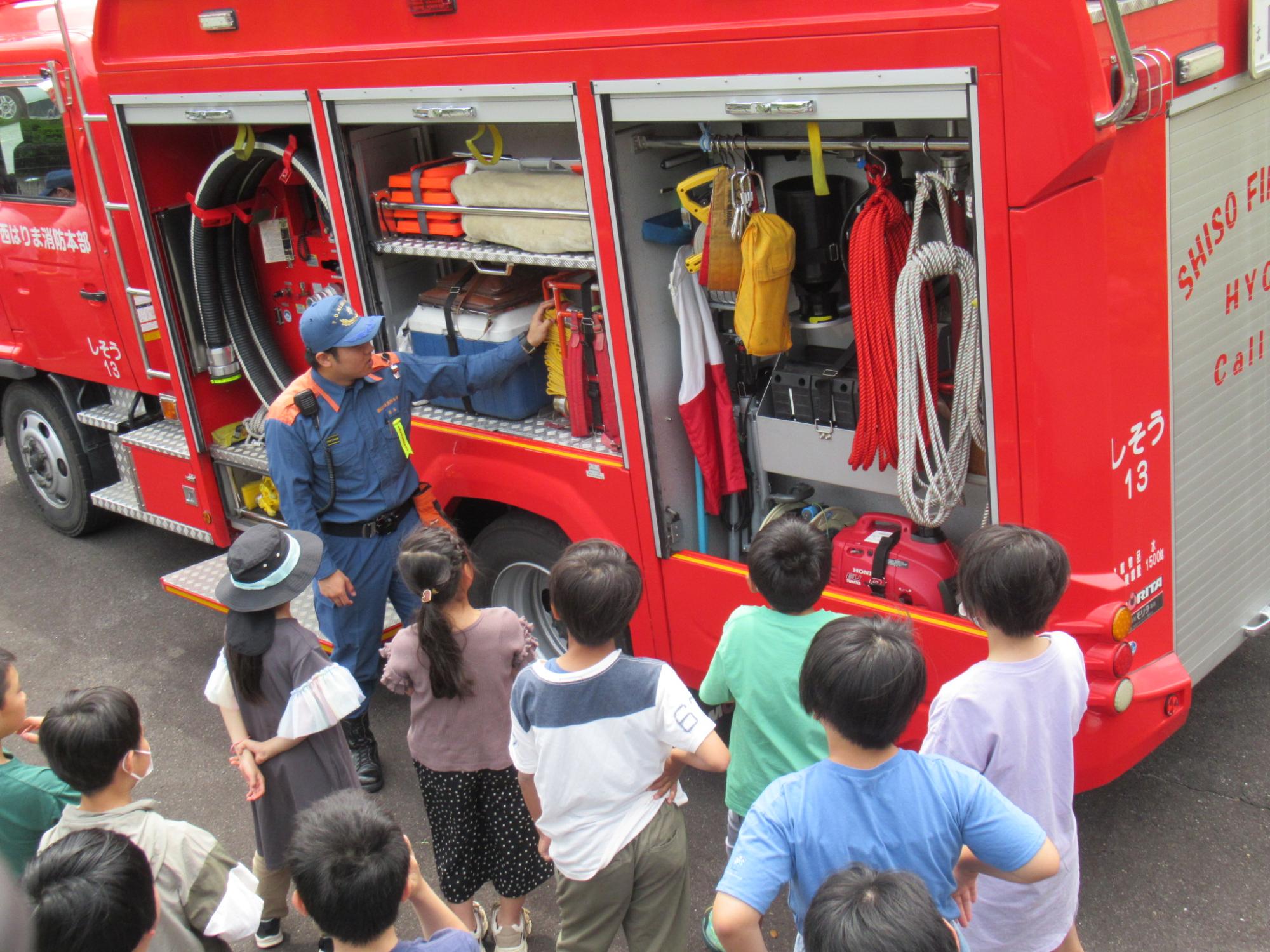 消防署員が消防車両の内部を披露し、参加者に搭載している設備などについて説明している写真