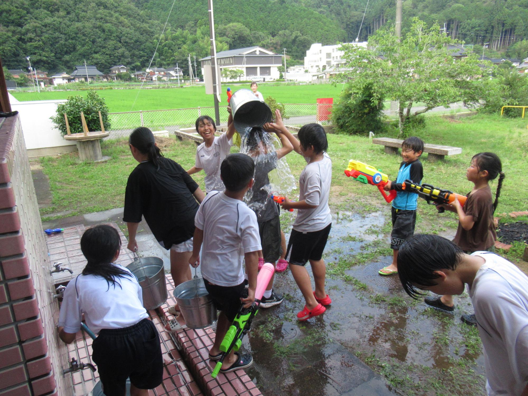 子どもたちが続々にバケツで水かけをし始め楽しんでいる写真