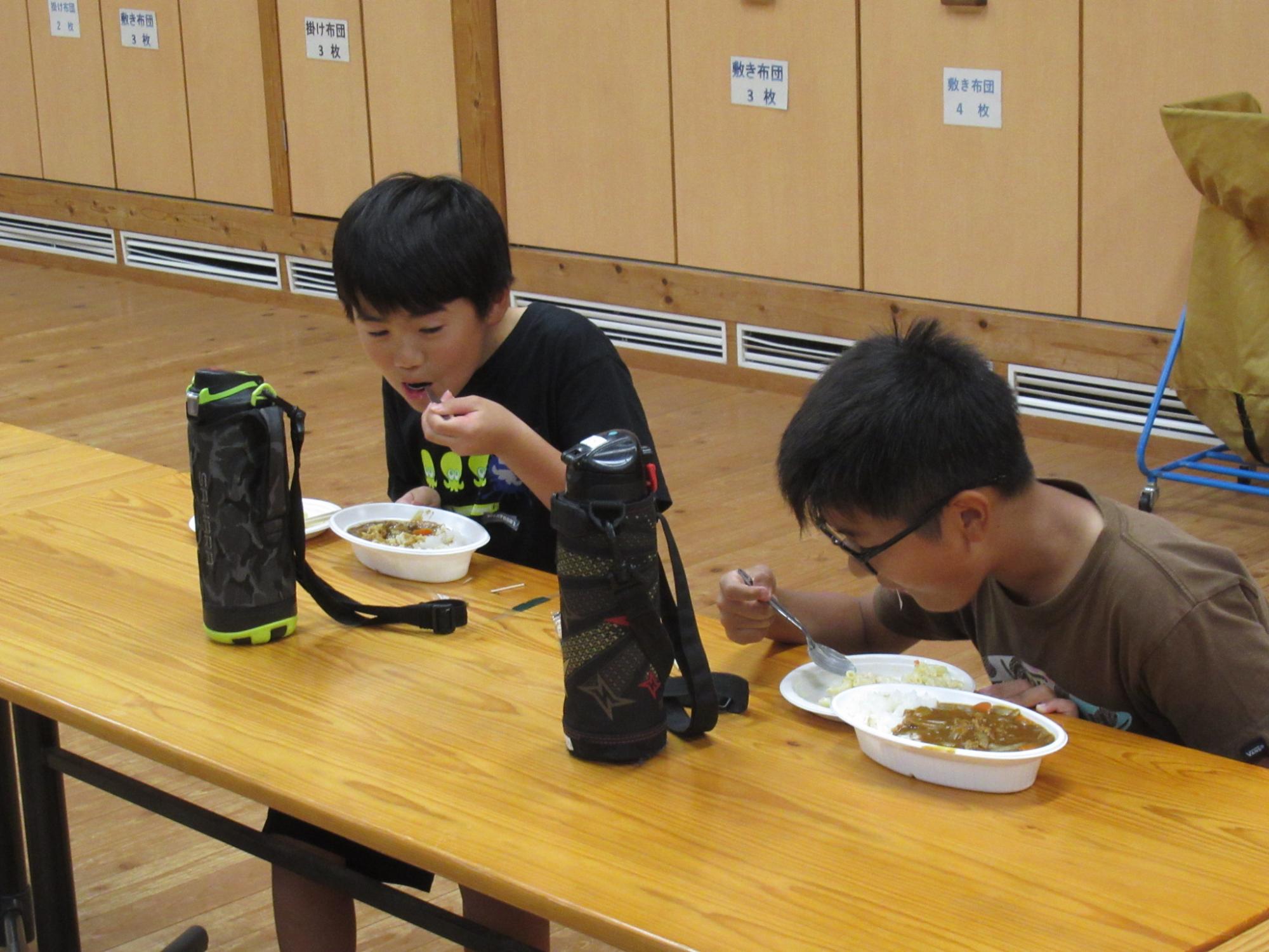参加者が完成したカレーを室内で食べている写真