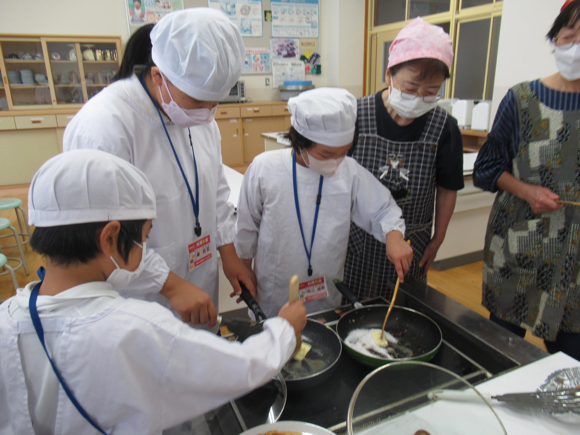 白い給食着を着た参加者がフライパンを熱してバターを溶かしている写真