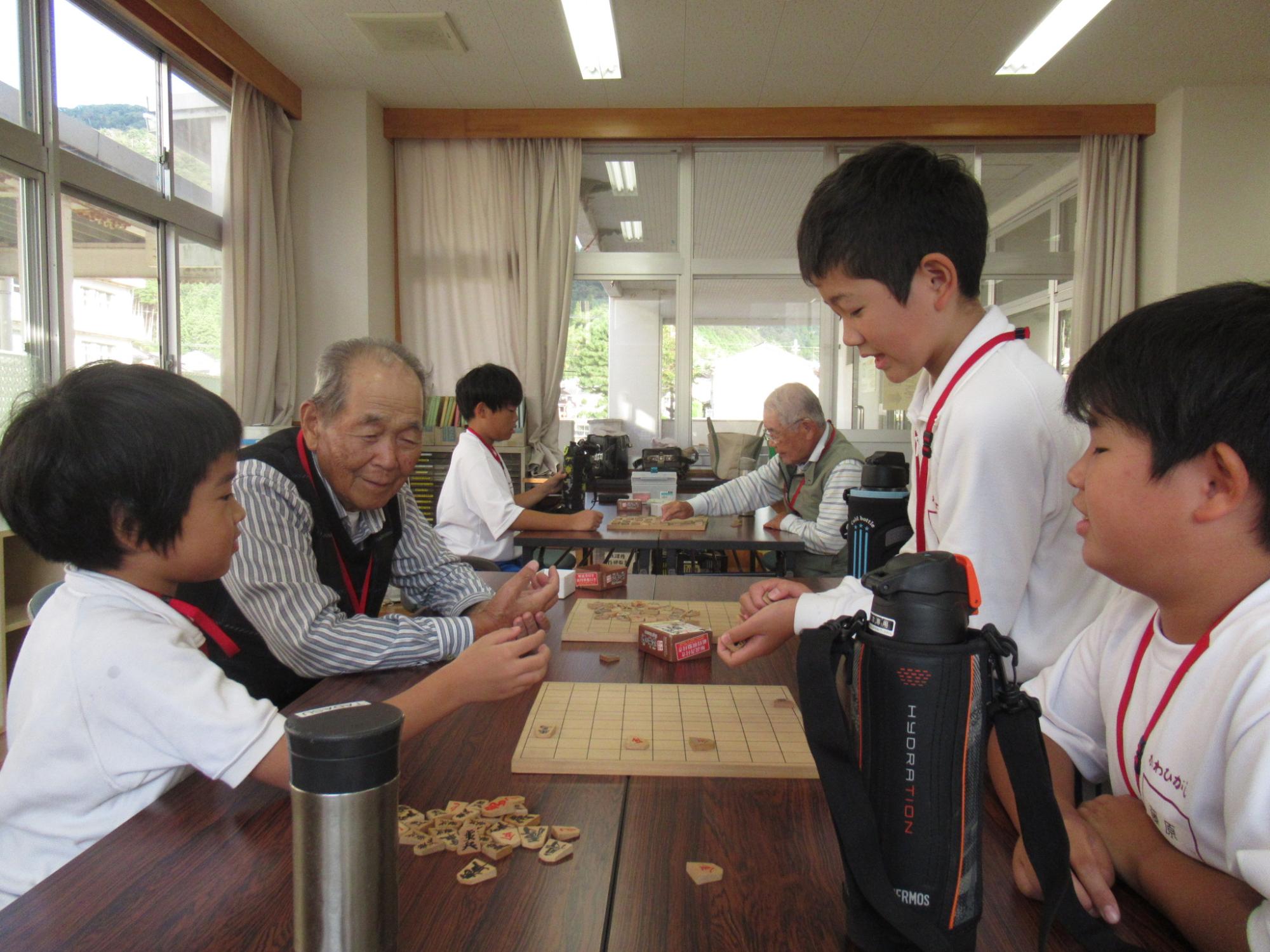 将棋の対局後に、講師と3人の参加者が一緒に回り将棋を楽しんでいる写真