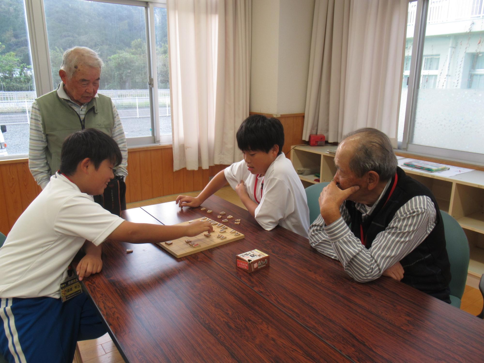 講師が隣で指導しながら参加者が将棋で対局している写真