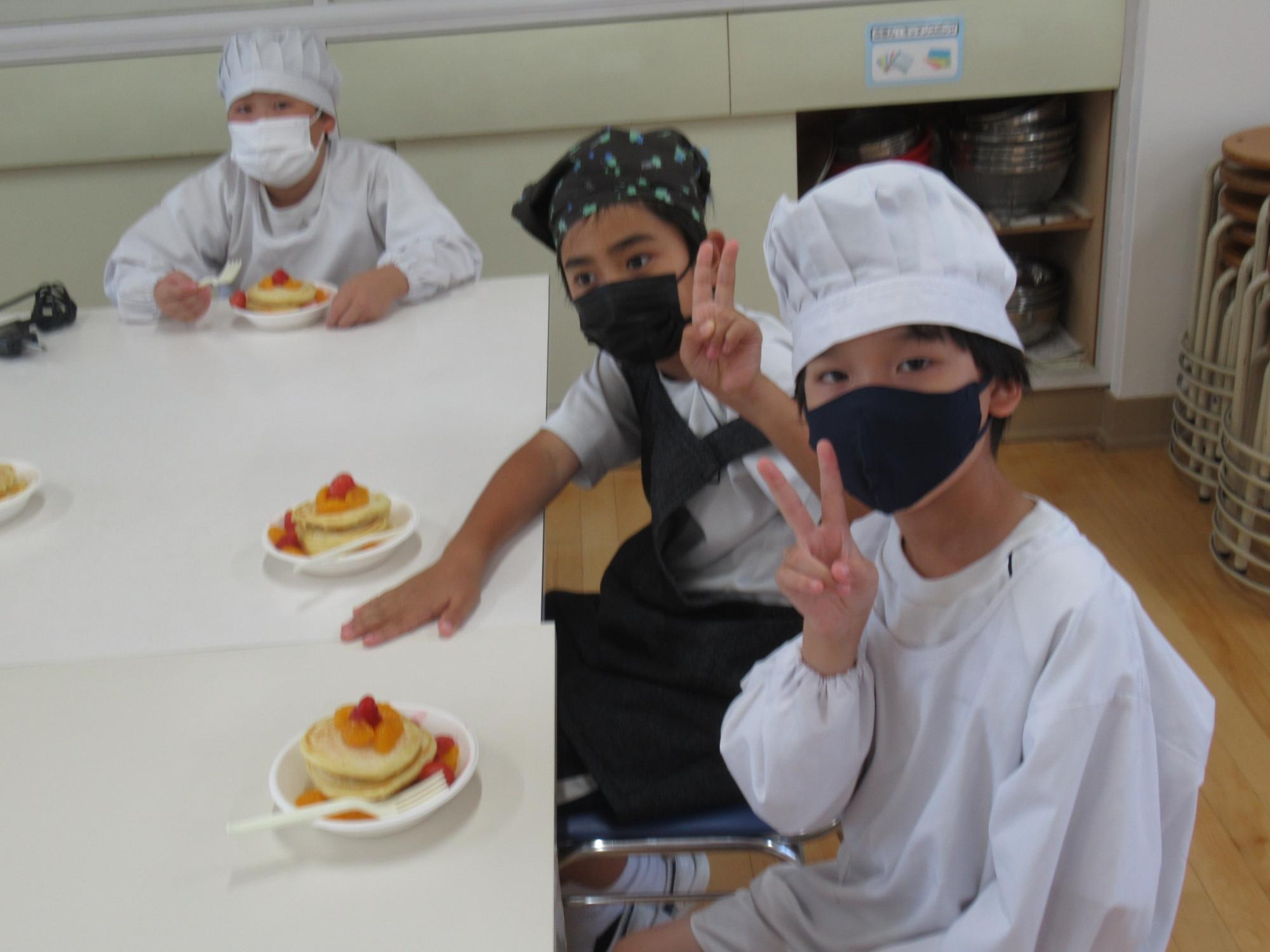 盛り付けが完了したパンケーキを食べ始める前に、参加者がカメラに向かってピースしている写真