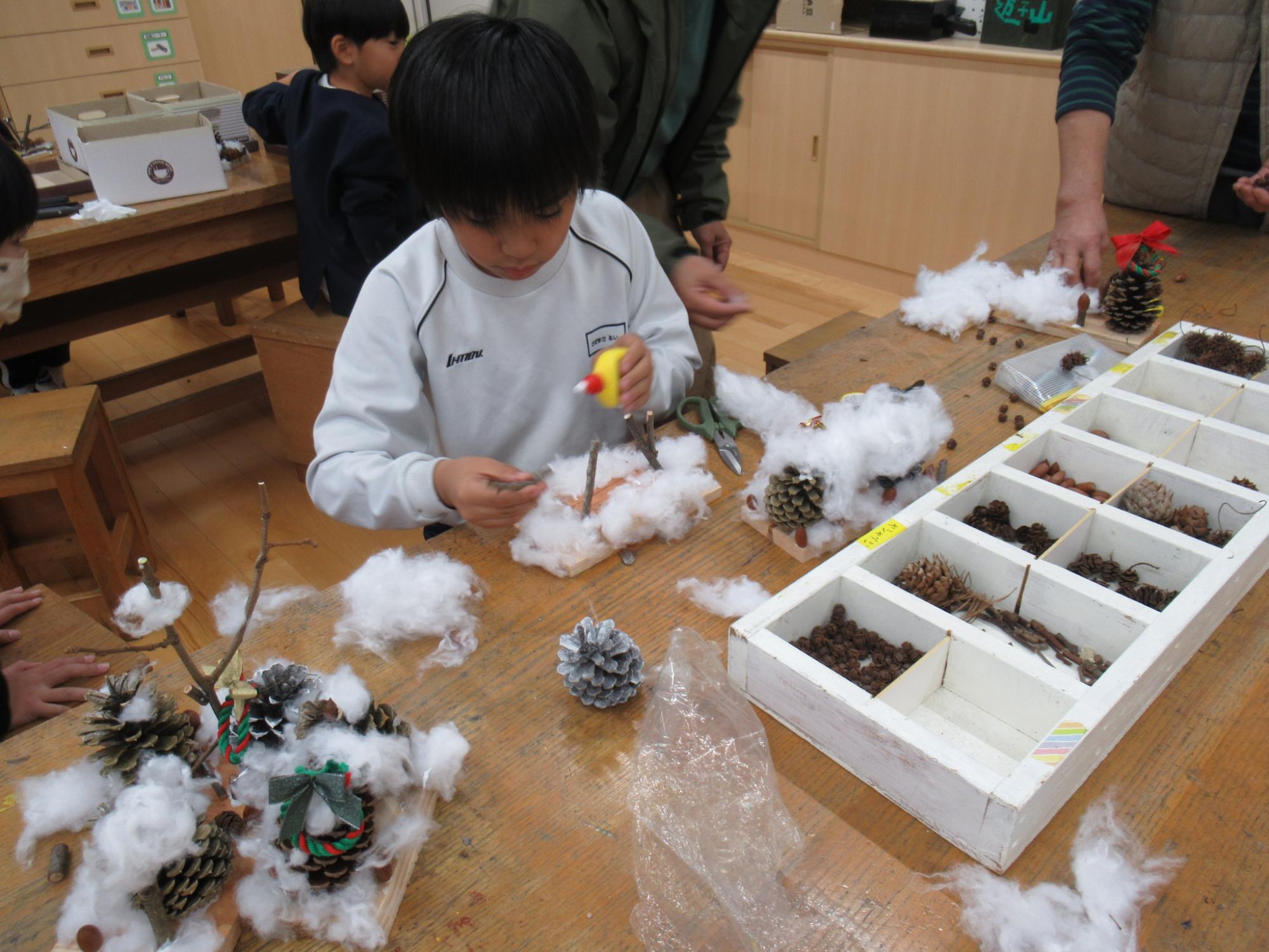 参加者が雪に見立てた綿を飾り付けている写真