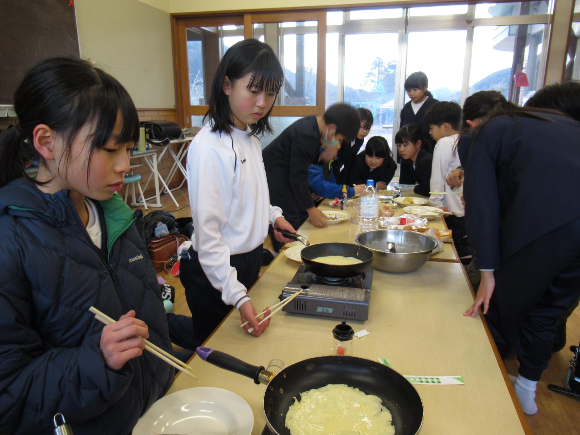 参加者がクレープ生地をフライパンで焼いてつくっている写真