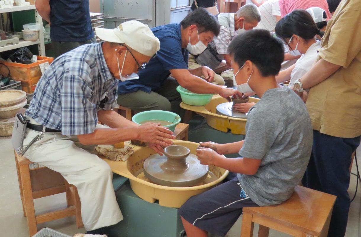 陶遊会メンバーから電動ろくろの使い方を教わりながらお皿づくりに挑戦する子どもたち