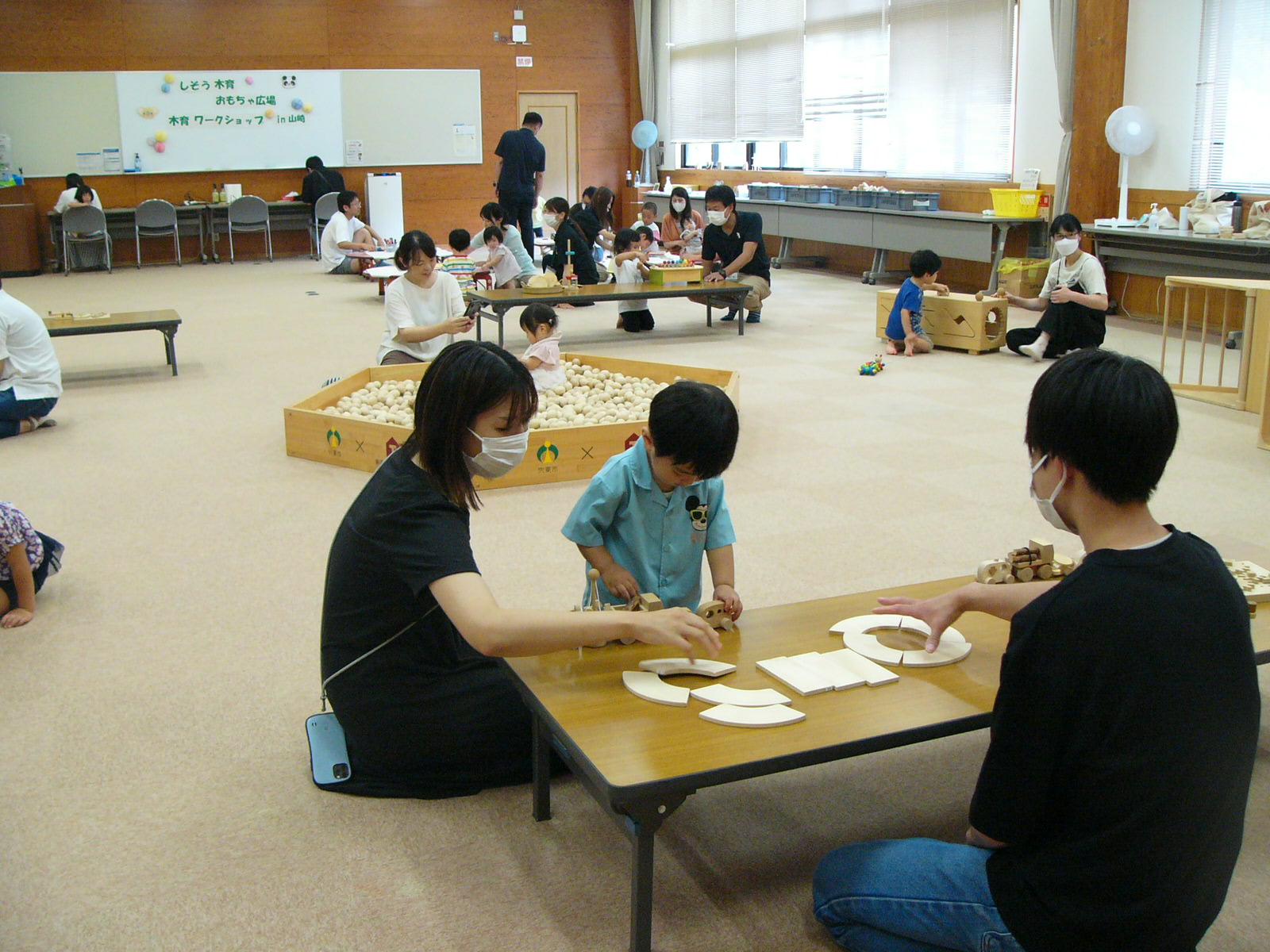 複数の参加親子が木製のおもちゃを使って遊んでいる写真