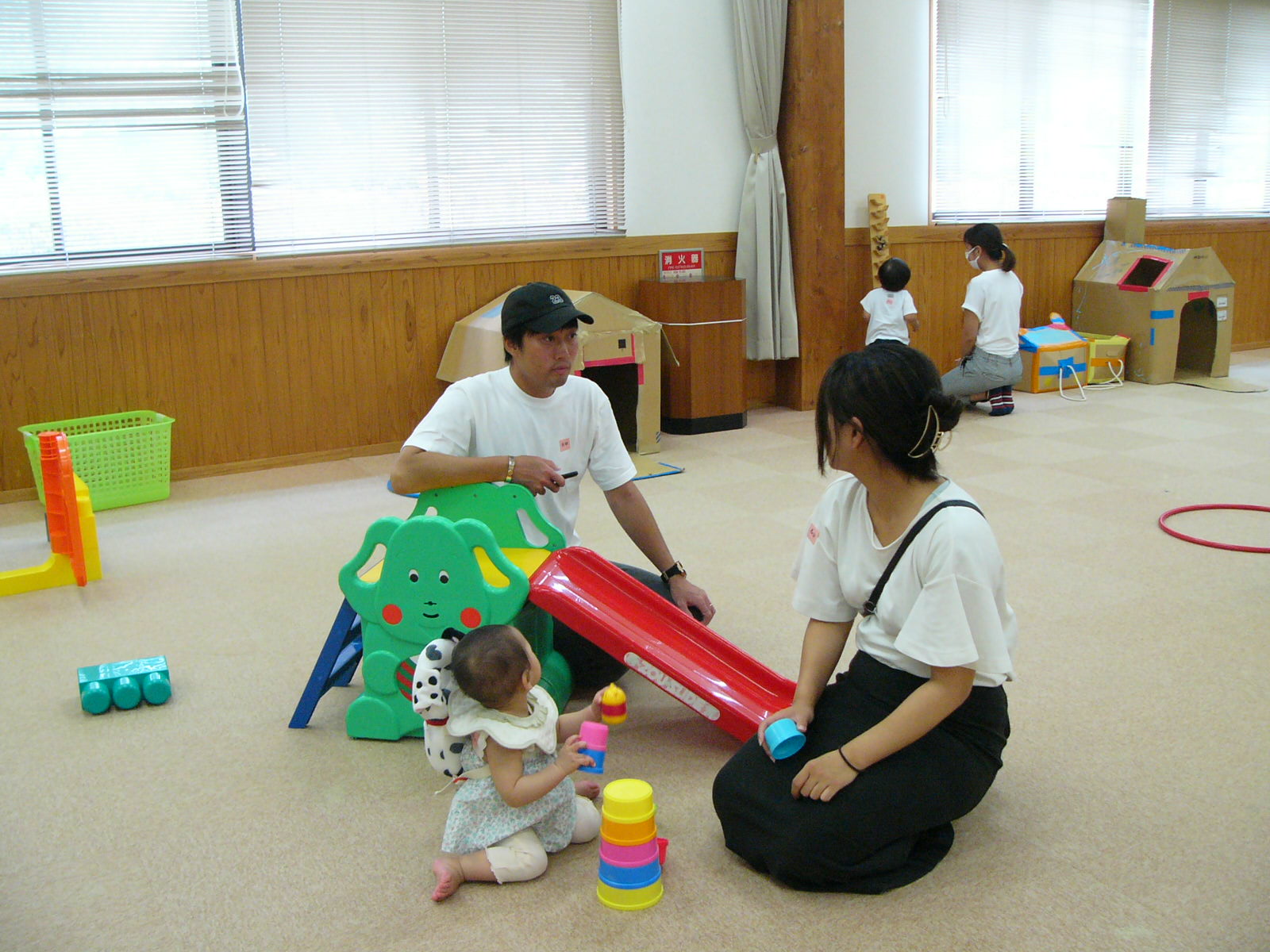 学遊館の室内にあるおもちゃを使って遊ぶ子どもとそれを見守る保護者の写真