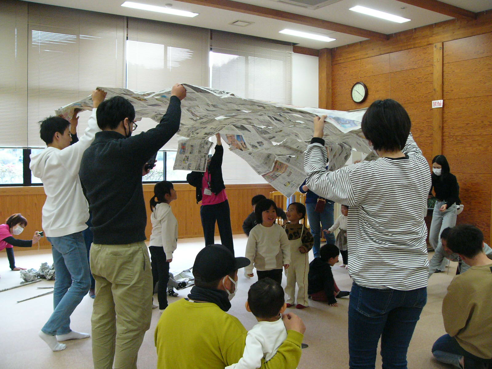 新聞紙をつなげて大きな風呂敷に見立てて参加者が遊んでいる写真