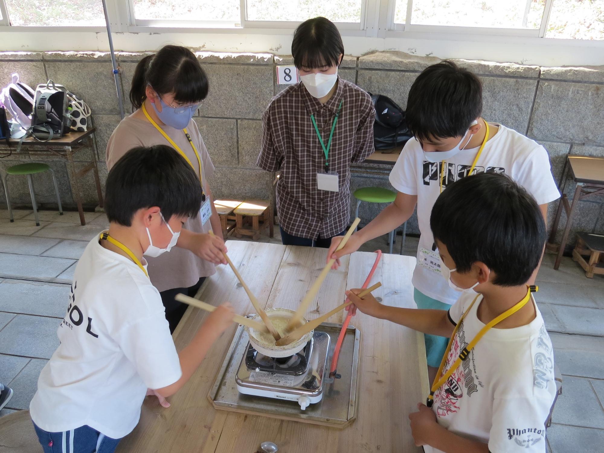 小さな土鍋で塩つくり体験をみんなでしている体験隊の子ども達の写真