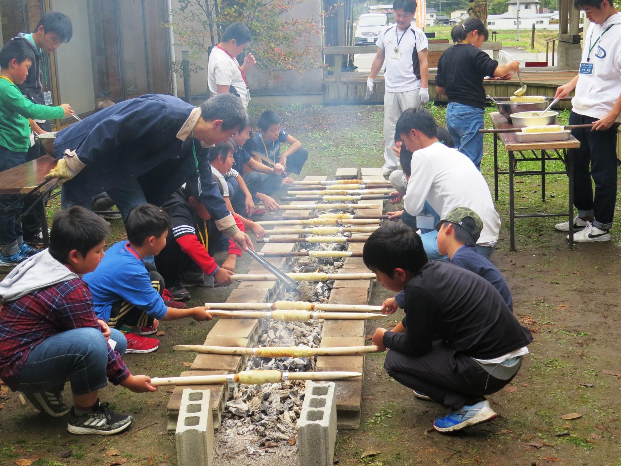 土曜なんでも体験隊バームクーヘン作りでみんなで焼いている写真