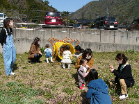 学遊館グラウンド端の原っぱの遊具で遊ぶ親子の写真
