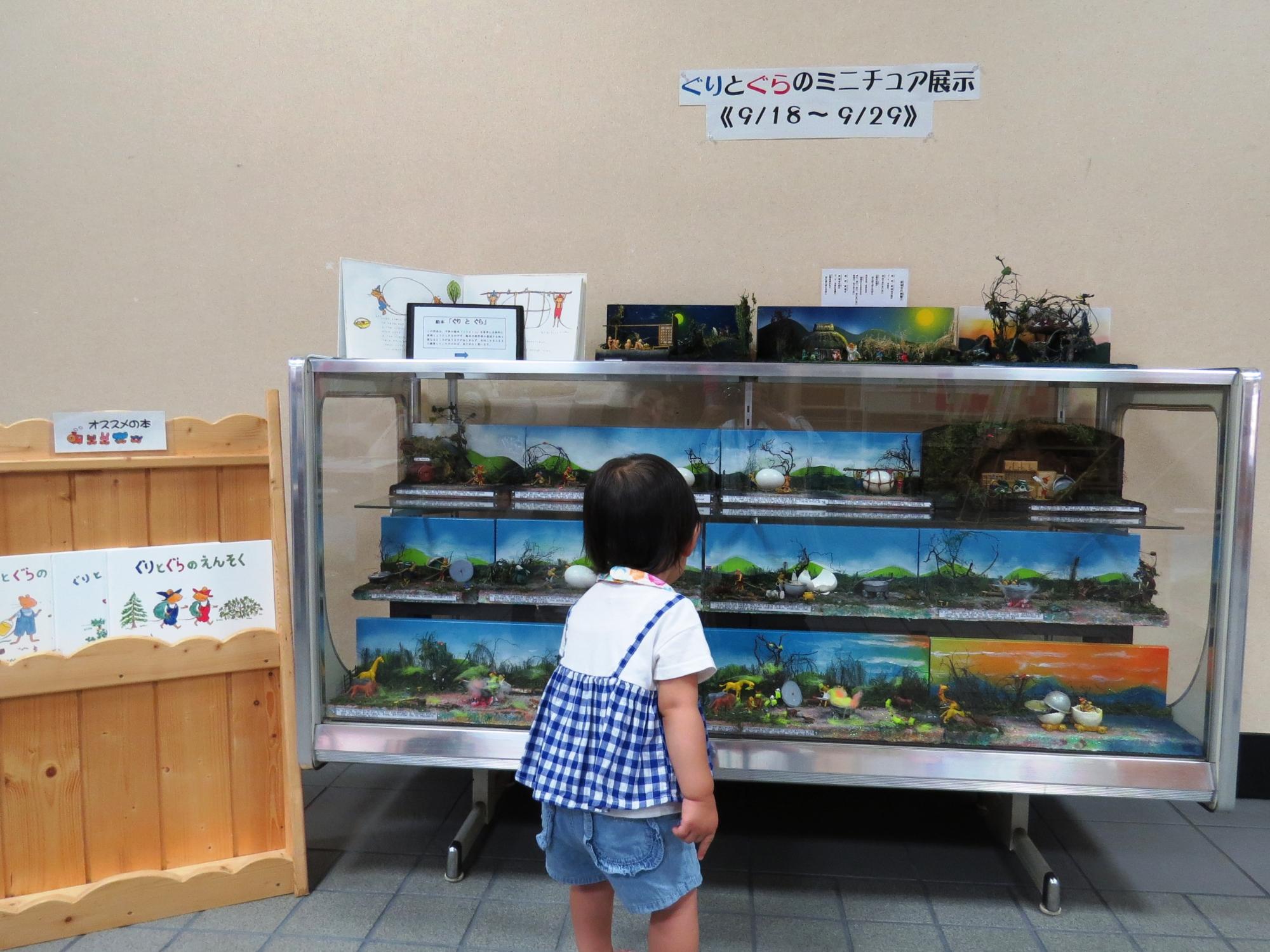 学遊館ロビーにてぐりとぐらのミニチュア展示を見ている小さな女の子の写真